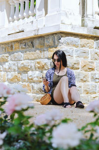 Portrait of young woman sitting on wall