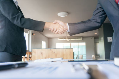 Midsection of colleagues shaking hands in office