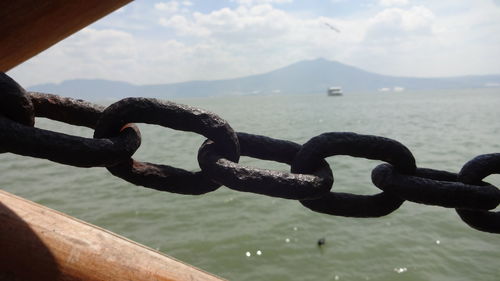 Close-up of chain by sea against sky