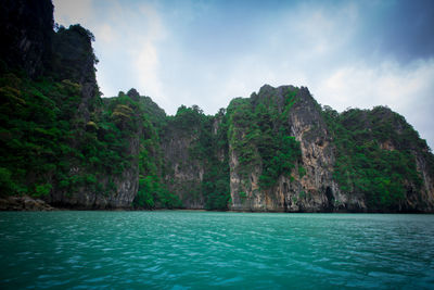 Scenic view of sea by mountains against sky