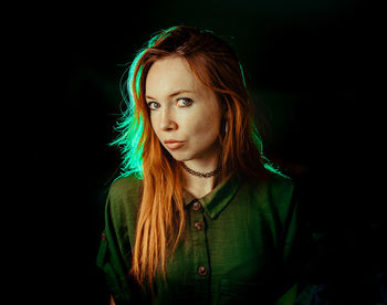 Portrait of young woman against black background