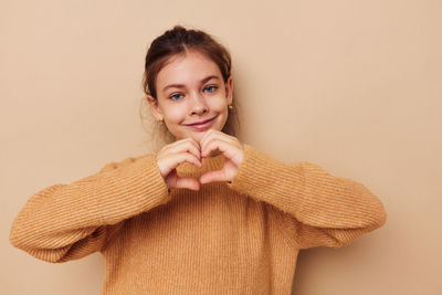 Portrait of young woman standing against pink background