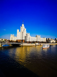 River by buildings against clear blue sky