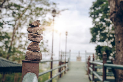 Close-up of stone stack on railing against sea