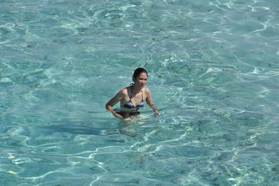 High angle view of mid adult woman wearing bikini swimming in sea