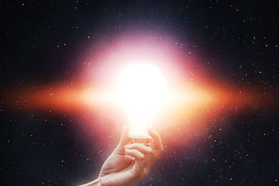 Close-up of hand holding illuminated light against star field