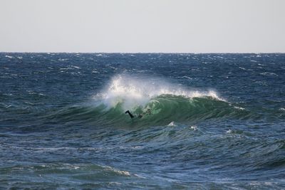 Man surfing in sea against clear sky