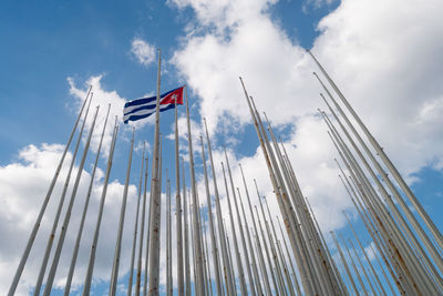 Low angle view of cuban flag amidst rusty metallic poles against sky