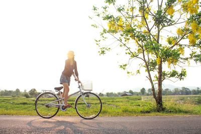 Woman riding bicycle on road against sky