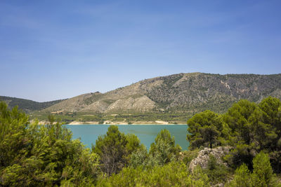 Scenic view of lake and mountains against blue sky