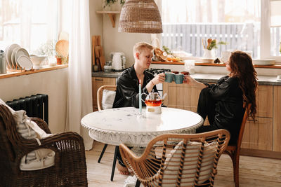 A couple in love have breakfast and drink tea in a decorated eco-style kitchen in a country house