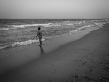 Rear view of woman on beach against sky