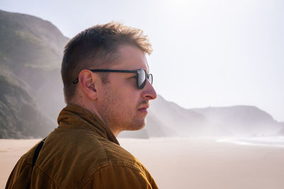 Portrait of young man wearing sunglasses against mountain