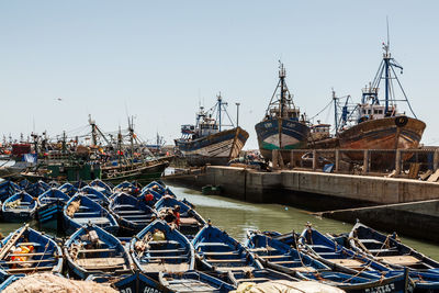 Boats moored at harbor against clear sky