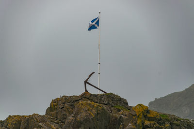 Low angle view of flag on mountain against clear sky