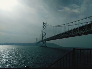 Bridge over calm sea against sky