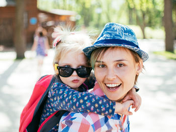 Portrait of smiling mother giving piggyback ride to daughter