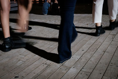 Low section of people walking on wooden floor