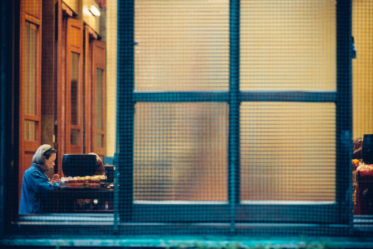 indoors, window, architecture, built structure, closed, building exterior, glass - material, door, house, lifestyles, pattern, men, metal, wall - building feature, standing, rear view, day, blinds