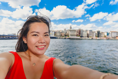 Portrait of smiling woman taking selfie against sea