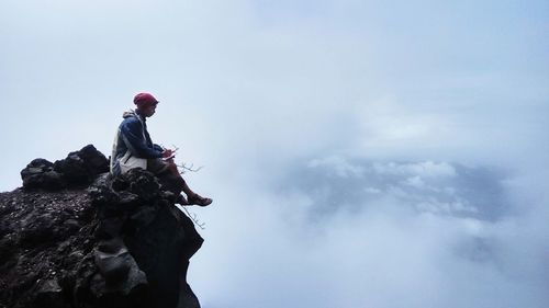 Rear view of man standing on mountain against sky