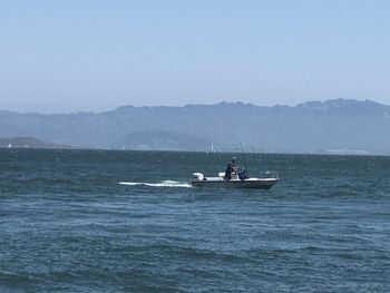 People on boat in sea against sky