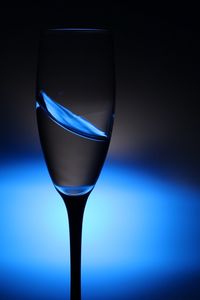 Close-up of champagne flute against illuminated blue light bulb