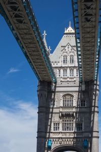 Low angle view of bridge and buildings against blue sky