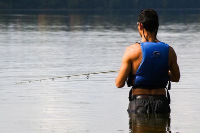 Rear view of man fishing in lake