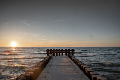 Pier over sea against sky during sunset