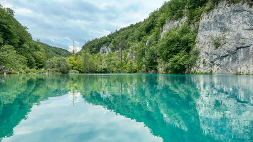 Scenic view of lake in plitvice by trees against sky