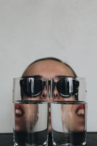 Close-up of drinking glasses with woman wearing sunglasses in background
