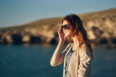Woman wearing sunglasses standing against sky