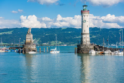 Lighthouse amidst sea and buildings against sky