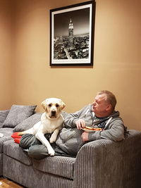 Man with dog sitting on sofa