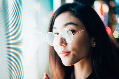 Portrait of young woman standing against illuminated city at night