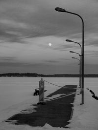 Street light by sea against sky during winter