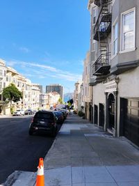 Cars on street by buildings against blue sky