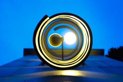 Low angle view of illuminated lamp against blue sky