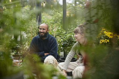 Smiling friends sitting in greenhouse