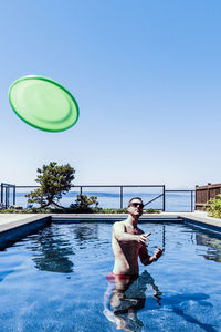 Full length of shirtless man in swimming pool against clear sky