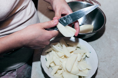 Cutting potato chips . knife in hands for cutting potatoes . home kitchen scene