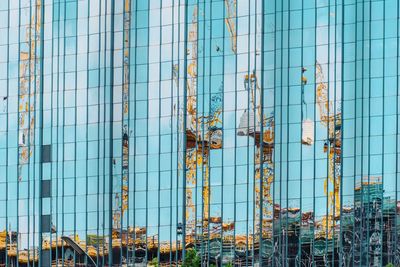 Reflection of cranes in modern glass building