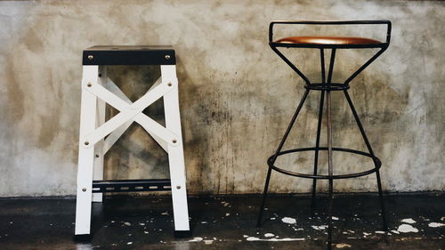 Empty chairs and table against wall