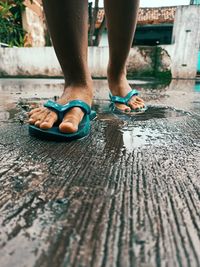 Low section of man standing on wet footpath