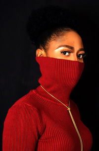 Portrait of woman modeling turtle neck shirt, half masked against black background