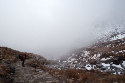 Rear view of man walking on foggy mountain
