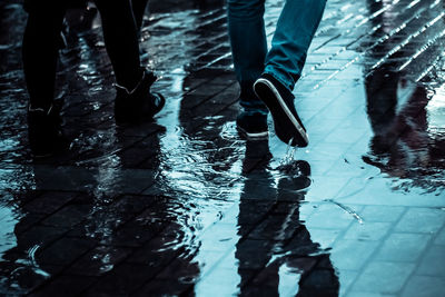 Low section of men walking on puddle during rainy season