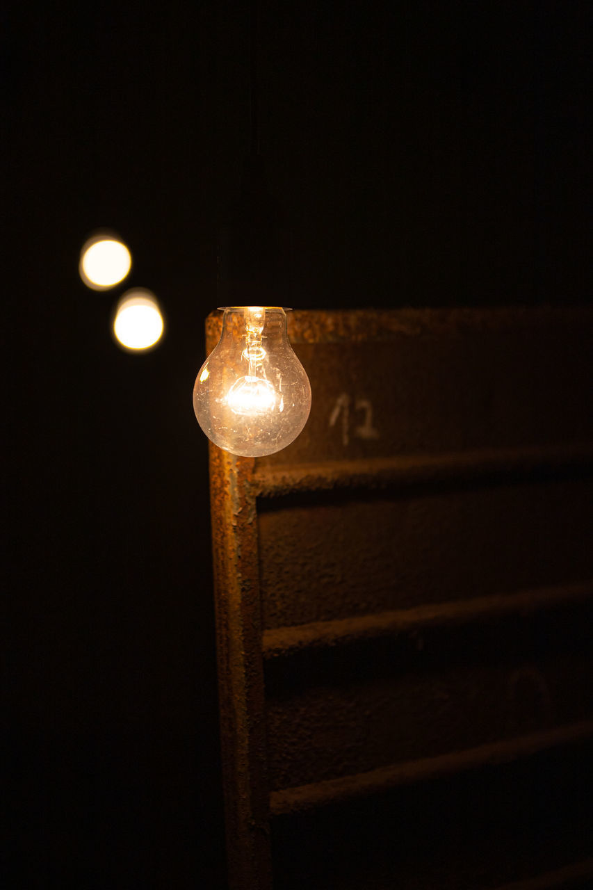 CLOSE-UP OF ILLUMINATED LIGHT BULB IN DARKROOM