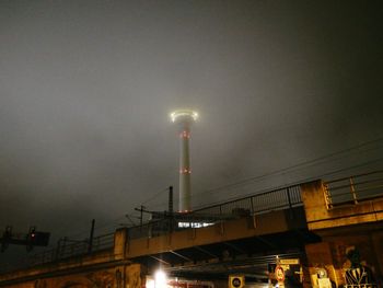 Illuminated factory against sky at night